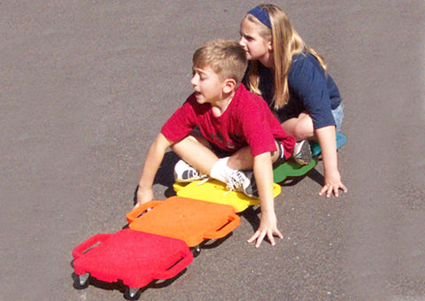 two young kids sitting on six connect-a-scooters that are linked together